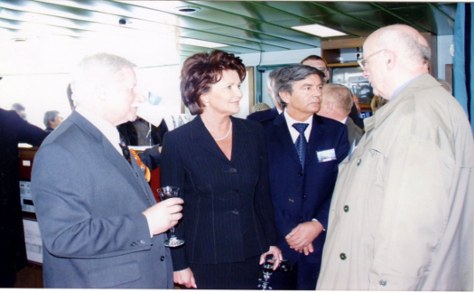 Na fotografii Pani Prezydentowa Jolanta Kwaśniewska w rozmowie z Generalnym Projektantem  (serii statków do przewozu 6.000 samochodów osobowych) mgr inż. Wojciechem Żychskim gratuluje znakomitemu projektantowi wyjątkowo udanej konstrukcji statku. Dodając z uśmiechem, iż z wielką dumą uczestniczy w zdarzeniach, kiedy Polska myśl techniczna rozsławia Polskę, jej projektantów i ludzi, którzy umieją przekuć tak wspaniały projekt w rzeczywisty wyrób najnowszej myśli technicznej jakim jest ten statek. Pomiędzy rozmówcami Prezes Stoczni Gdynia S.A p. Jerzy Lewandowski. Z kieliszkiem w ręku K-k Biura Budowy wspomnianego samochodowca  p. Władysław Szczepkowski. Fotografia ze zbiorów p Wł. Szczepkowskiego.